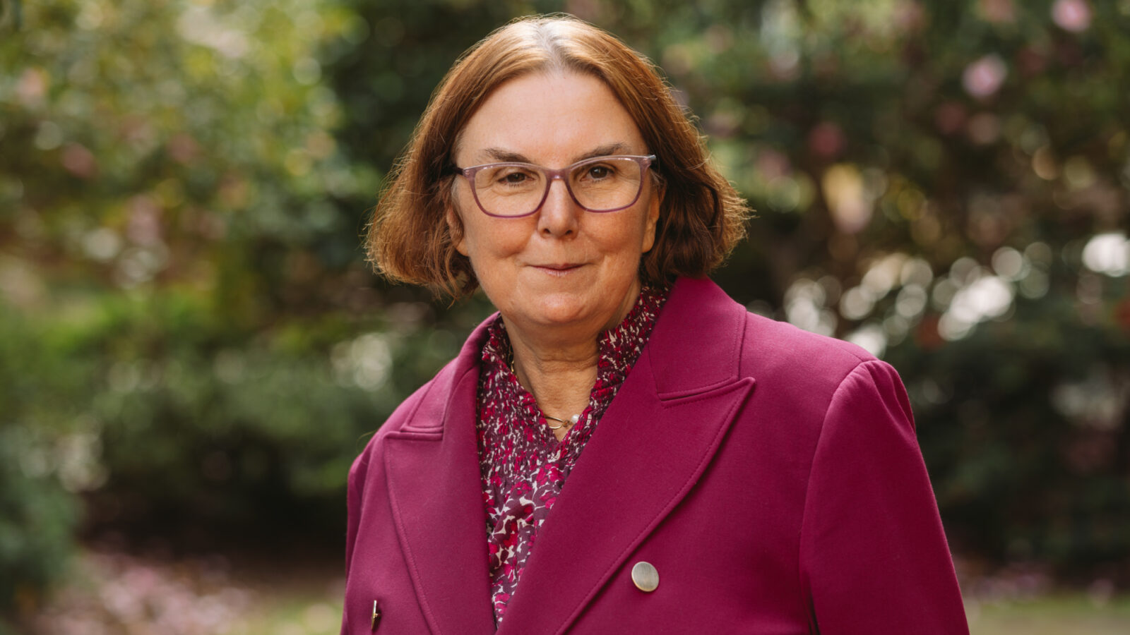 A photo of a professor, in a dark red jacket with short brown hair