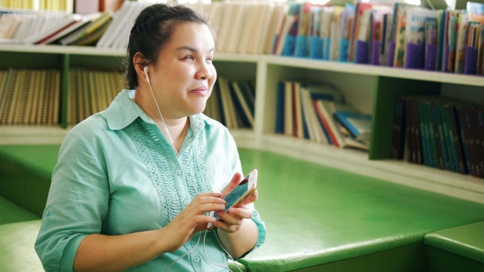 A young woman listens to audio through her phone.
