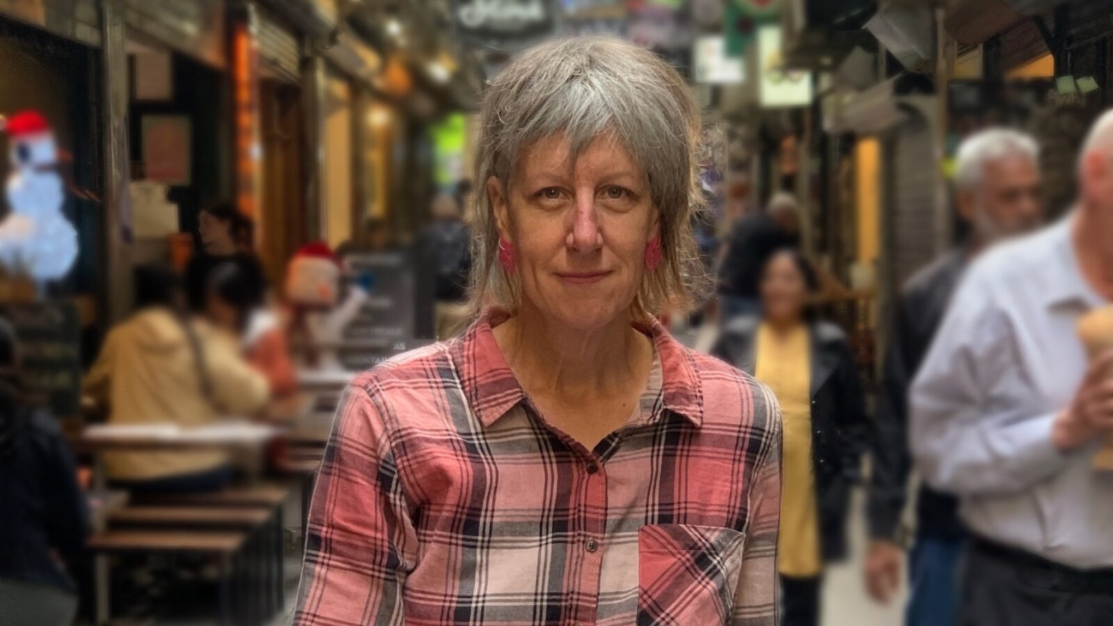 Heidi Everett sitting on a wooden stool in a laneway