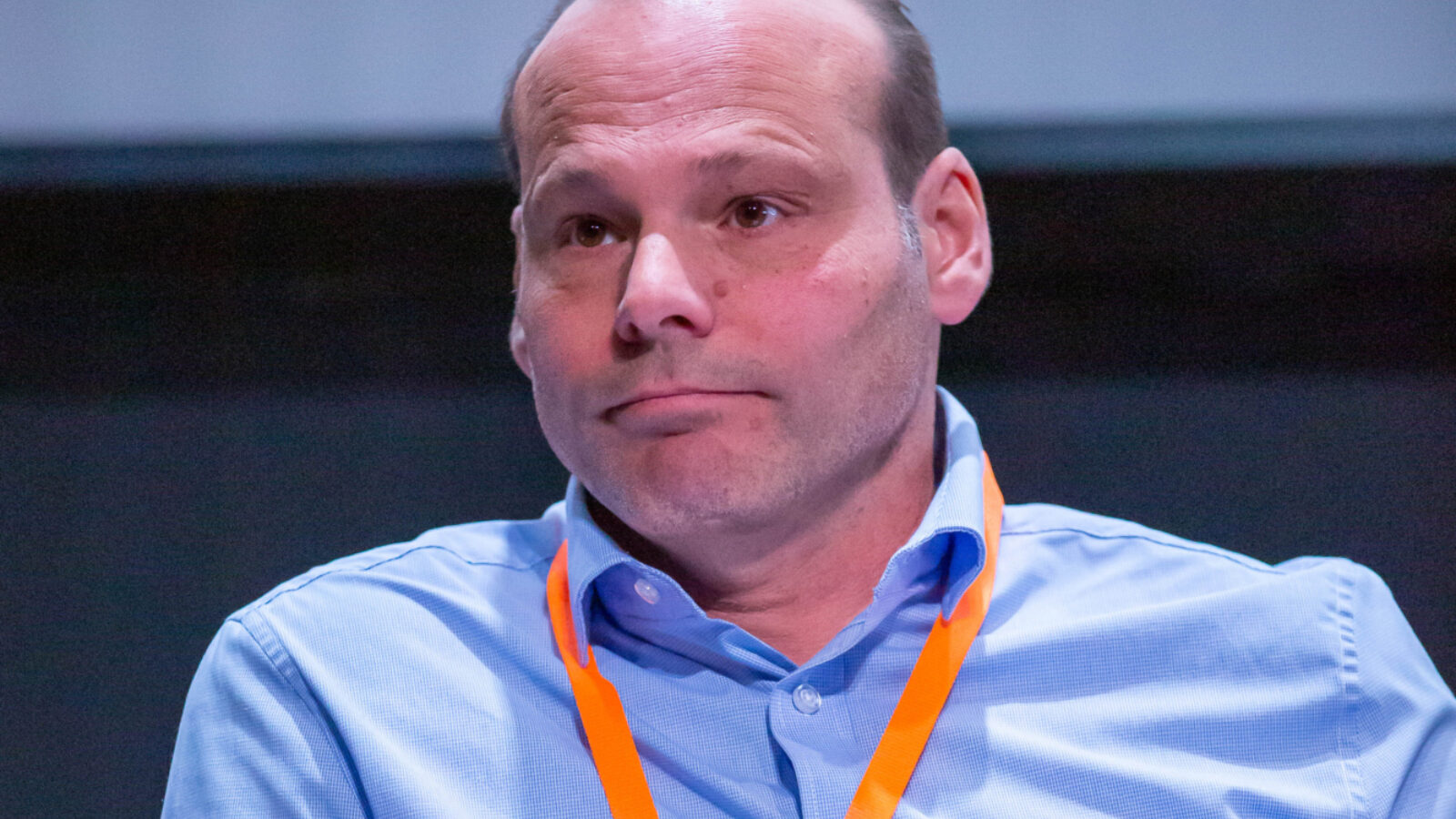 Anthony Risoli on stage in a blue shirt and with an orange lanyard