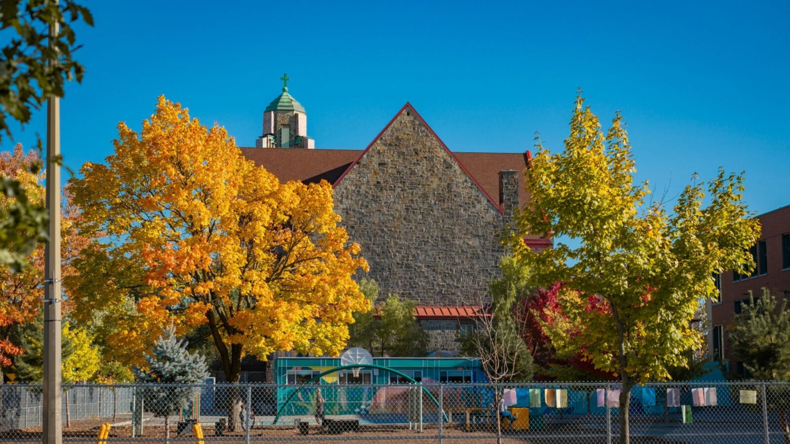 An old school building with autumn trees and a small playground.