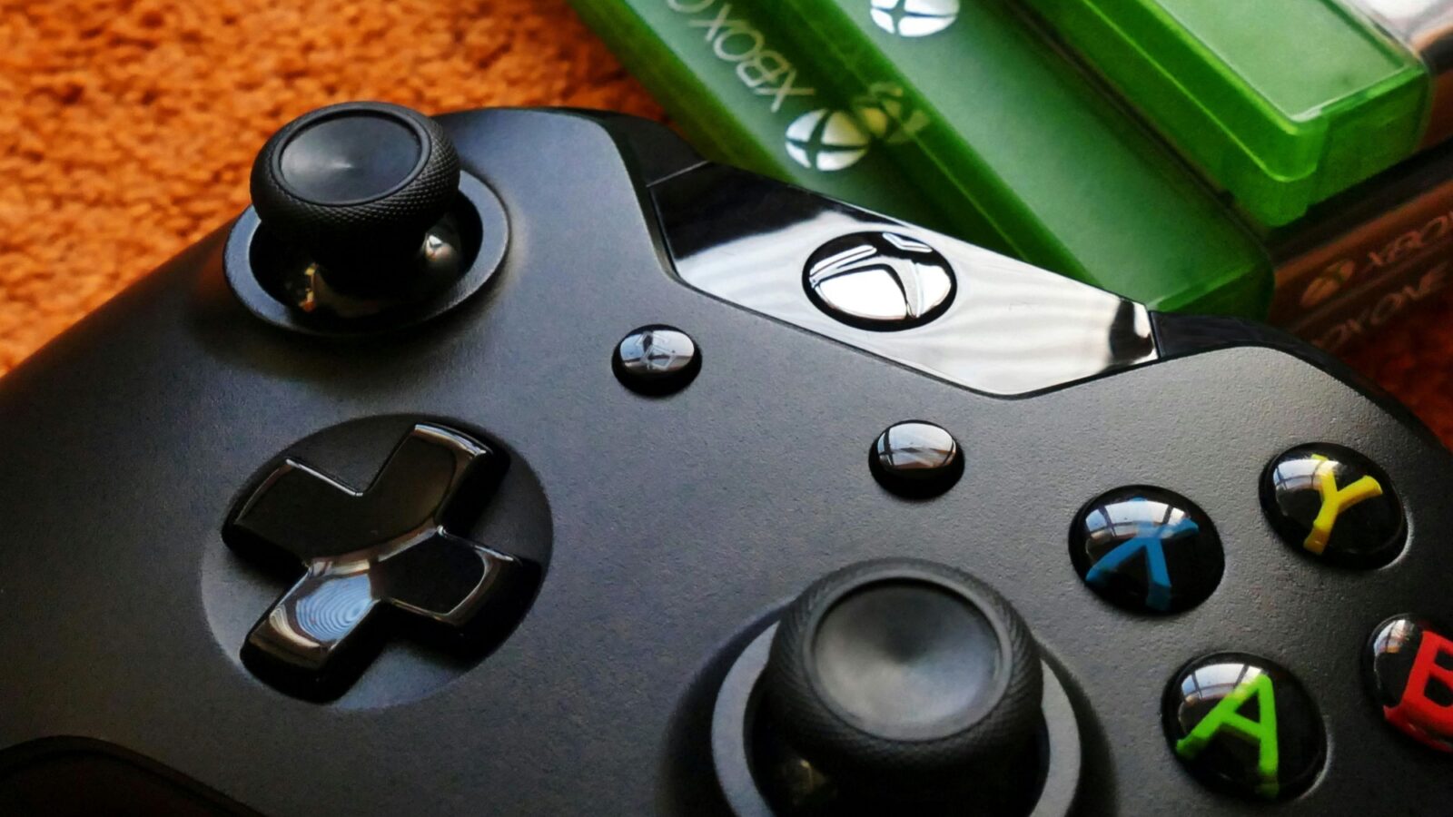 A black Xbox controller sits next to some xbox games
