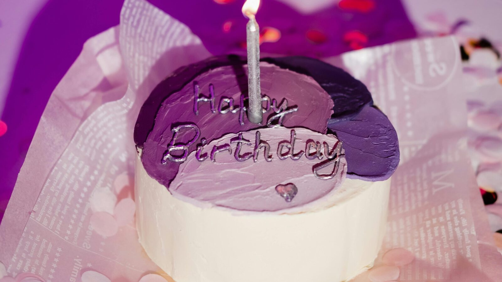 a purple birthday cake with a single candle
