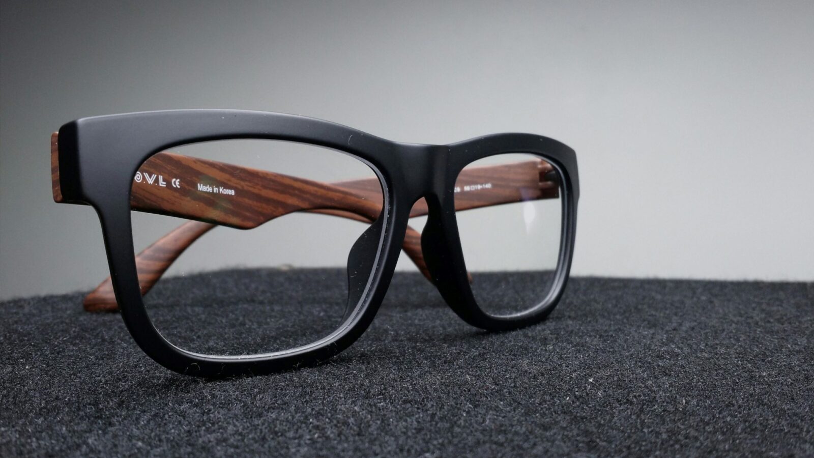 A pair of black and wooden glasses, resting on a dark surface.