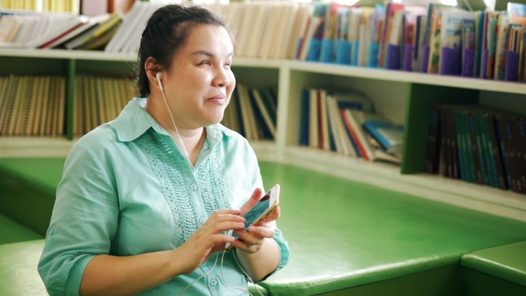 A young woman listens to audio through her phone.
