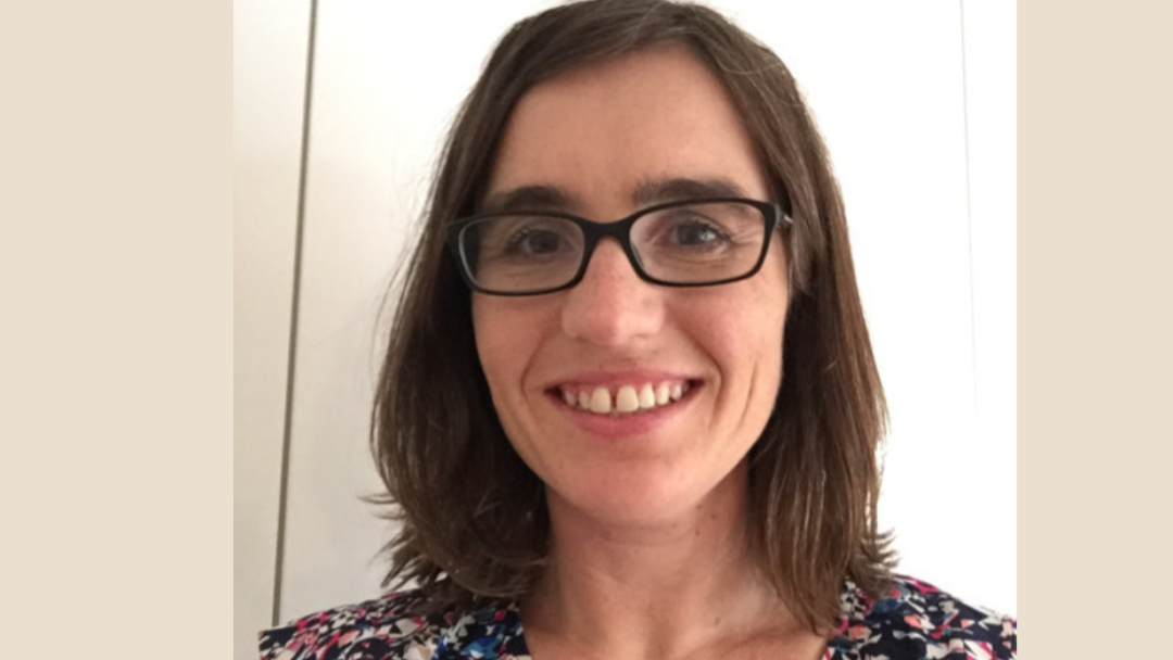 Woman with brown hair and glasses, smiling.