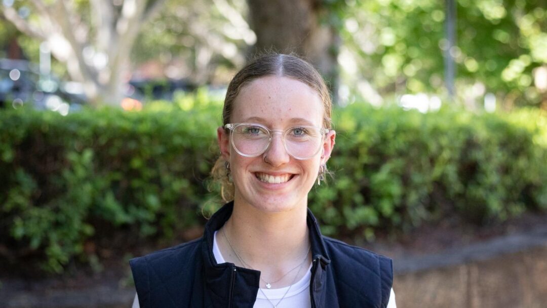 Justice, a smiling young woman in a white shirt and dark vest