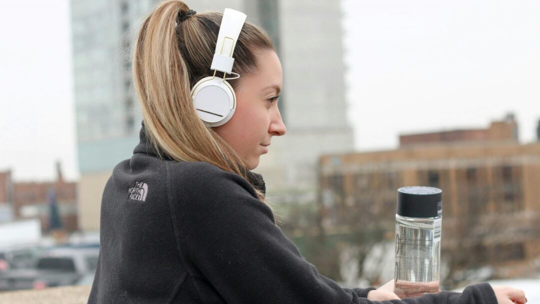 A person with white headphones on looks over a city