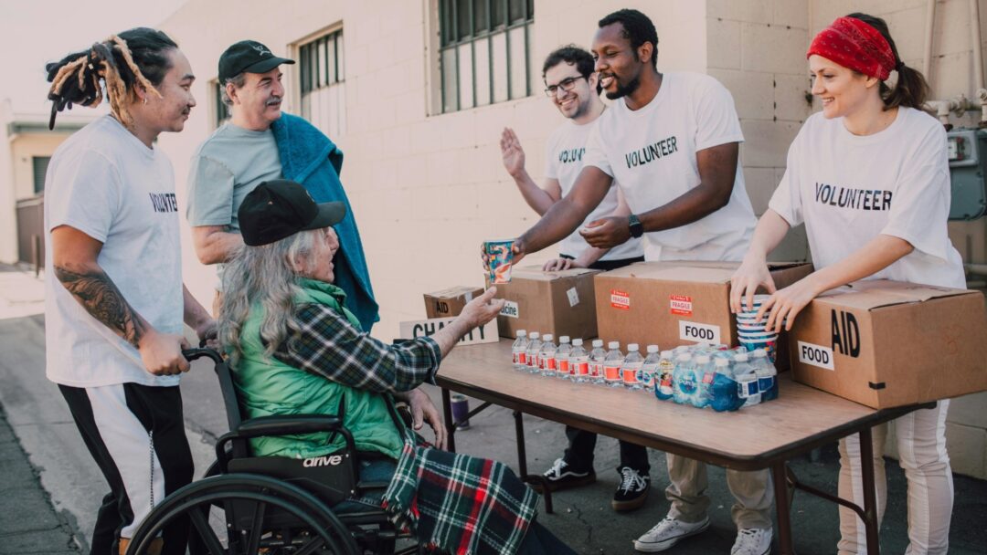 A staged stock photo of volunteers handing out water to a wheelchair user