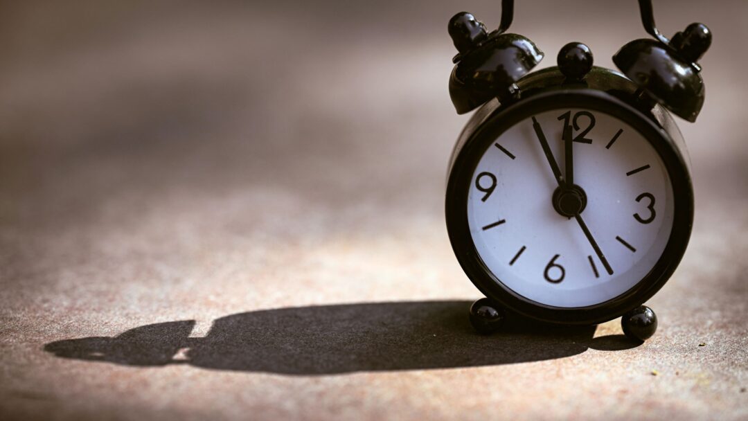 A black alarm clock with a heavy shadow