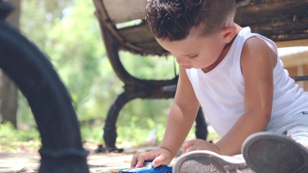 A child playing with a toy car on the ground