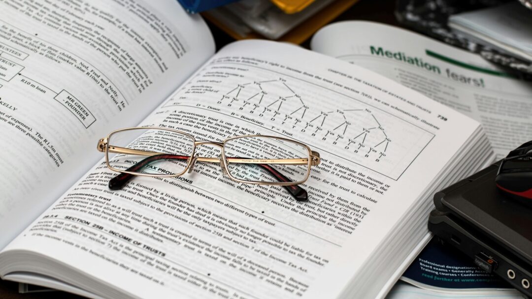 Reading glasses sitting folded on an open textbook