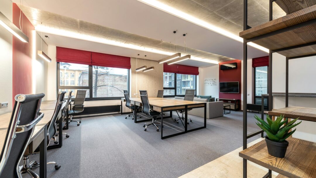 An empty open plan office space with dark chairs and light tables