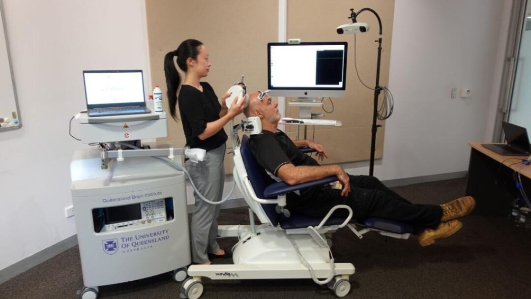 A person in a medical chair, reclined, having ultrasound therapy on their head