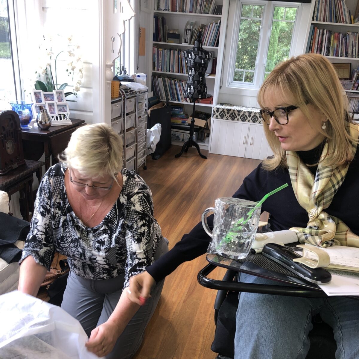 Carol Taylor in a power chair with people adjusting one of her designs.
