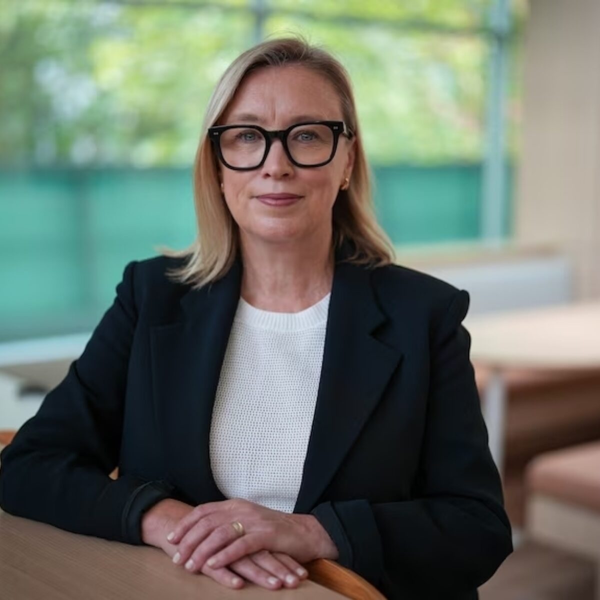 Nicole Rogerson a white woman with blonde hair in a black suit jacket and white shirt.
