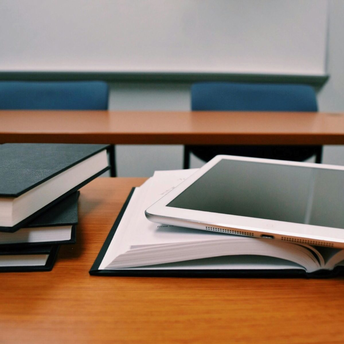 A tablet computer resting on a pile of books in a classroom