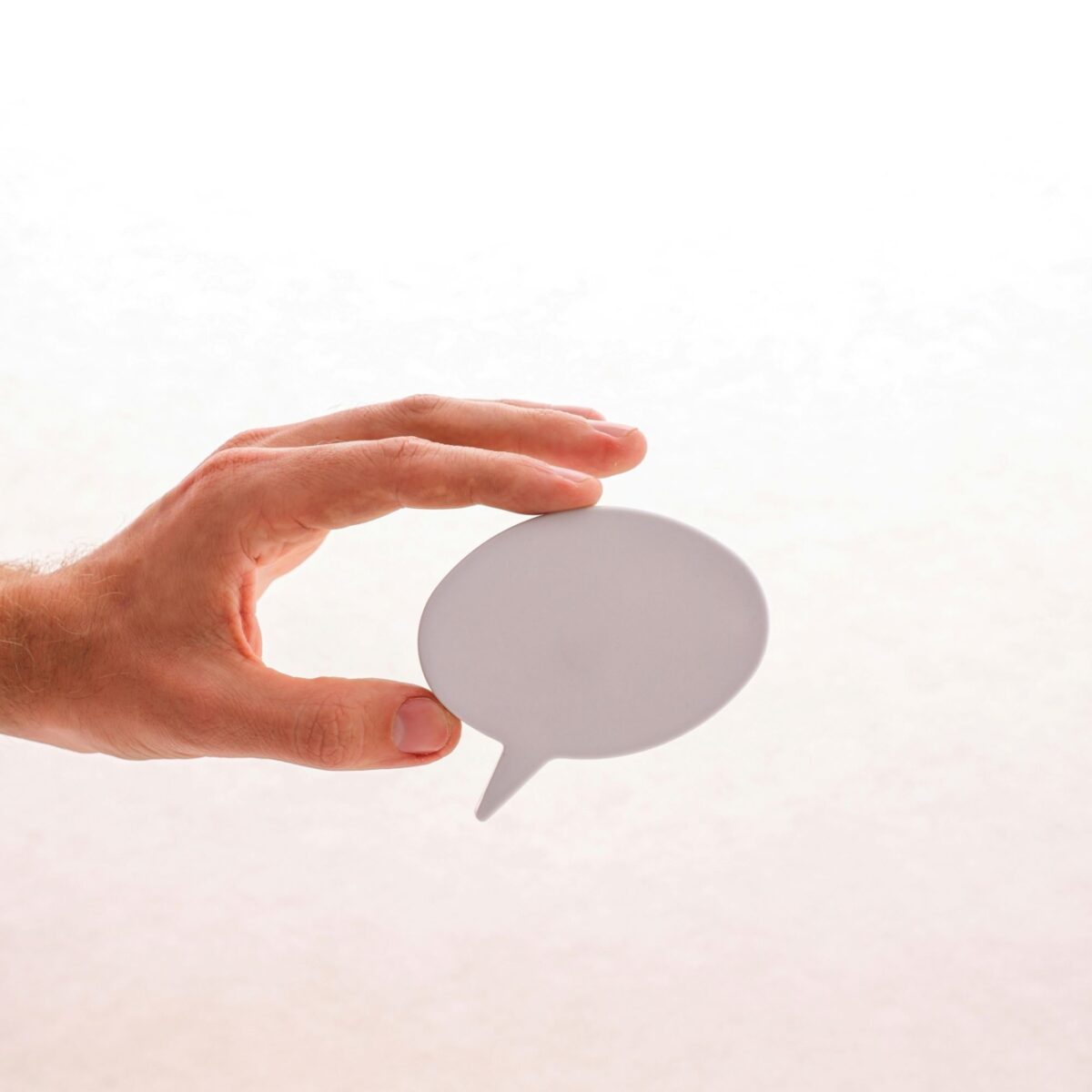 A hand holding a speech bubble against a white background
